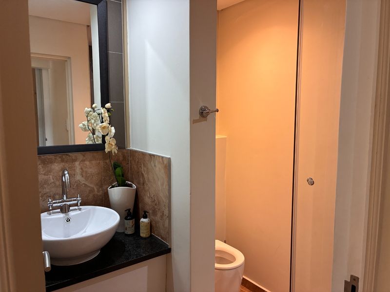 A functional bathroom featuring a modern vessel sink on a granite vanity, a wall-mounted mirror, and a separate toilet area.