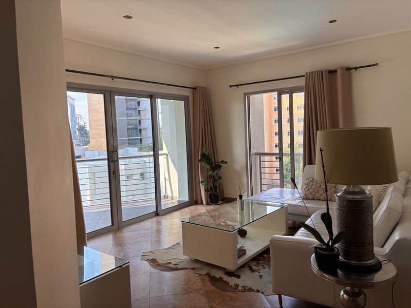 Spacious living room featuring tiled flooring, recessed lighting, and large sliding glass doors providing access to a private balcony.