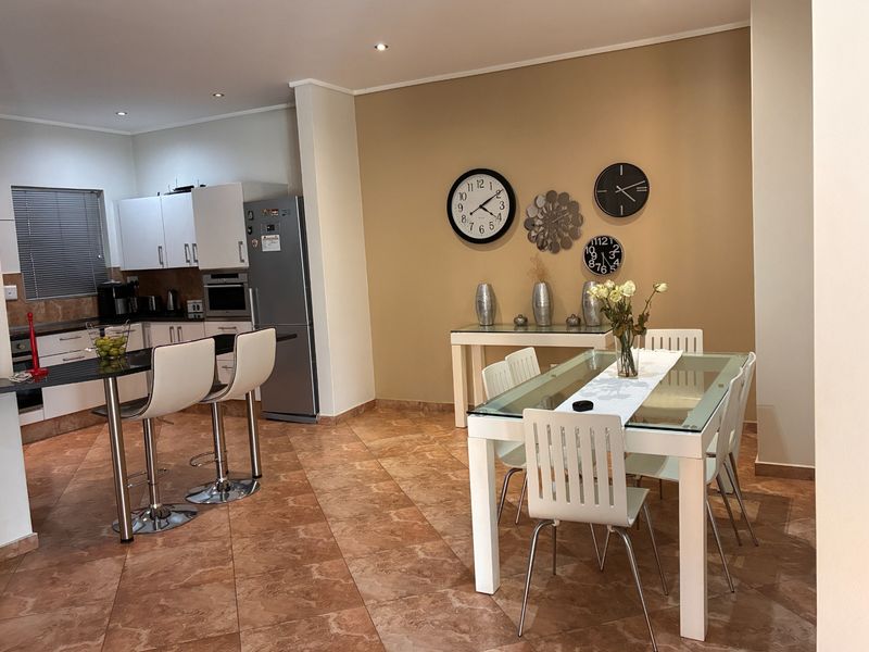 Open-plan kitchen and dining area featuring tiled flooring, modern cabinetry, granite countertops, and recessed lighting, creating a functional and cohesive living space.