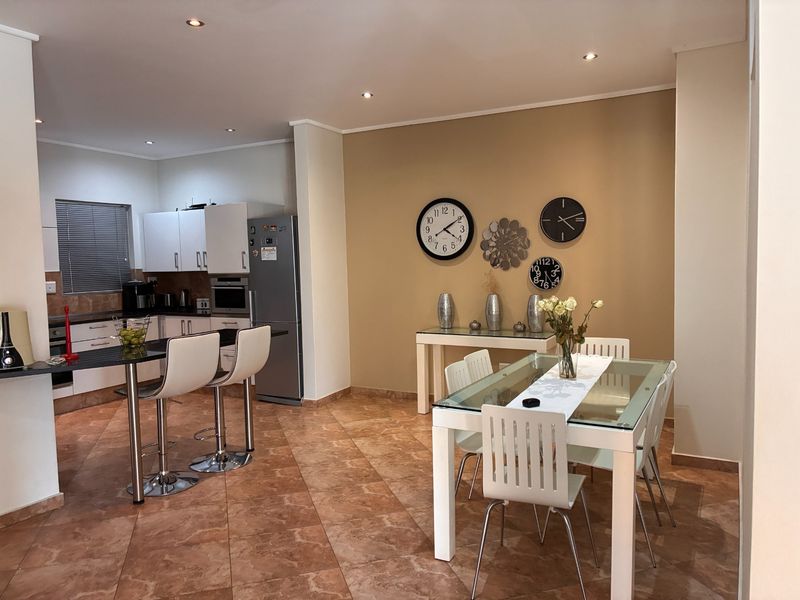 Open-plan kitchen and dining area featuring tiled flooring, modern cabinetry, granite countertops, and recessed lighting, creating a functional and cohesive living space.