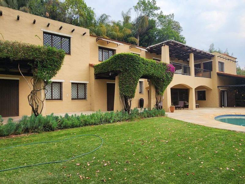 Spacious rear exterior featuring a swimming pool, covered patio area, balcony, and traditional stucco facade with mature landscaping.