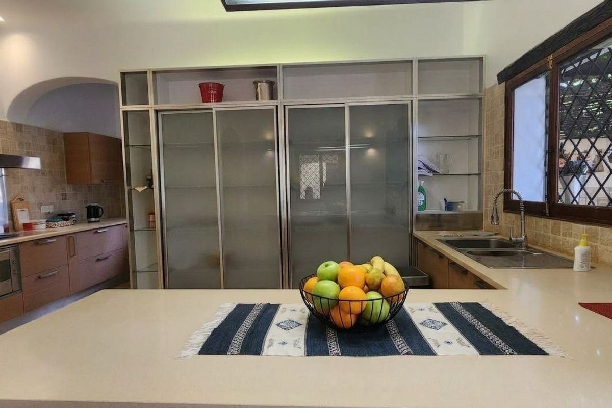 A well-appointed kitchen featuring stone countertops, built-in oven, gas hob, extractor fan, and ample cabinetry with frosted glass detailing.