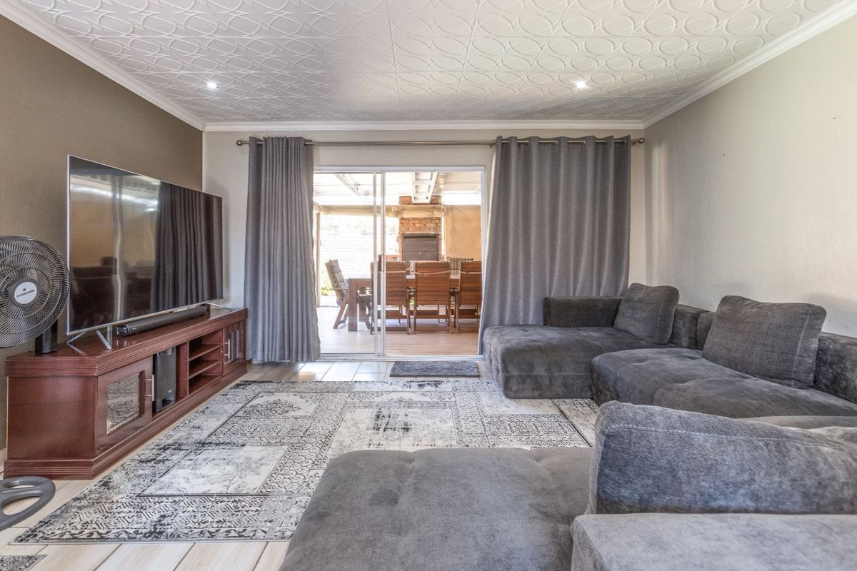 Spacious living room featuring a decorative patterned ceiling, recessed lighting, and large sliding glass doors providing direct access to the outdoor patio area.