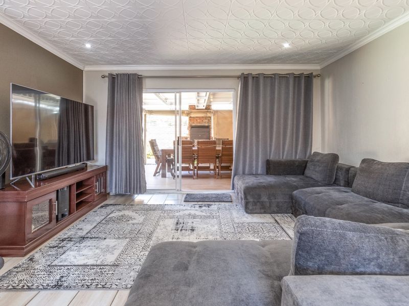Spacious living room featuring a decorative patterned ceiling, recessed lighting, and large sliding glass doors providing direct access to the outdoor patio area.