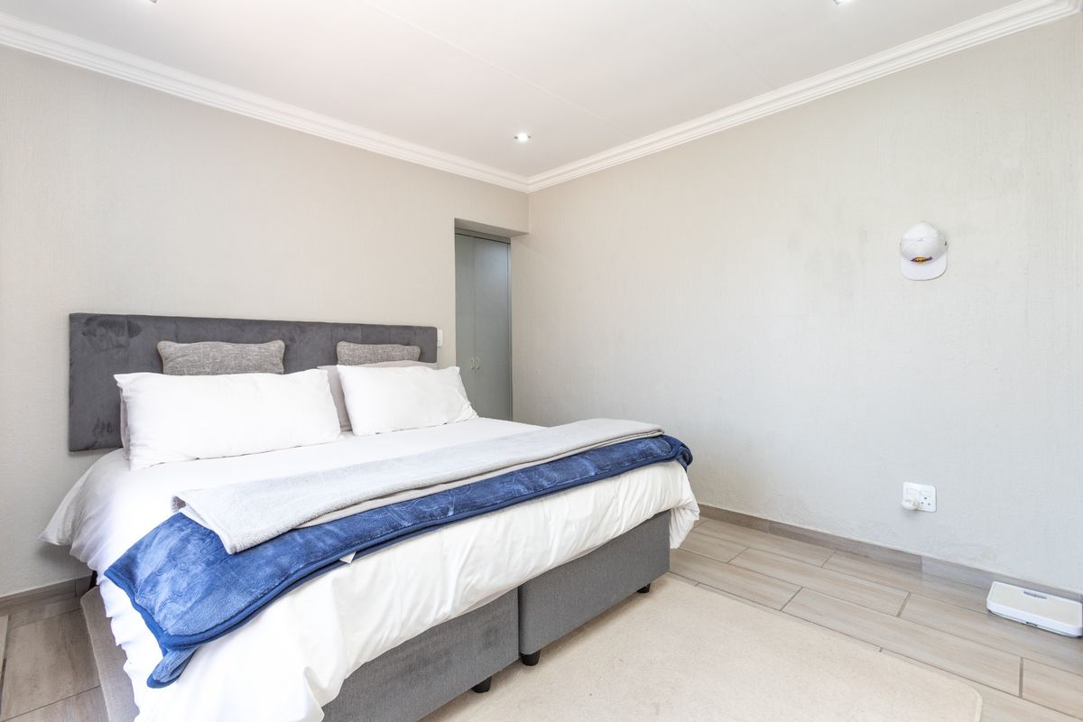 A well-maintained bedroom featuring tiled flooring, recessed downlighting, decorative ceiling cornicing, and a built-in cupboard.
