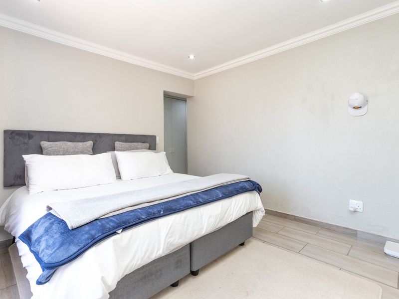 A well-maintained bedroom featuring tiled flooring, recessed downlighting, decorative ceiling cornicing, and a built-in cupboard.