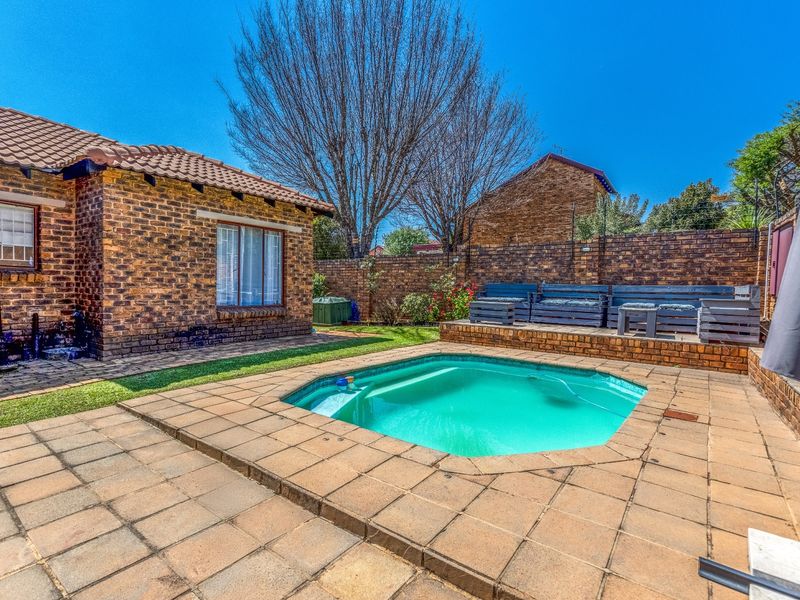 A private backyard featuring a swimming pool, paved patio area, and facebrick exterior walls, enclosed by a secure brick boundary wall.