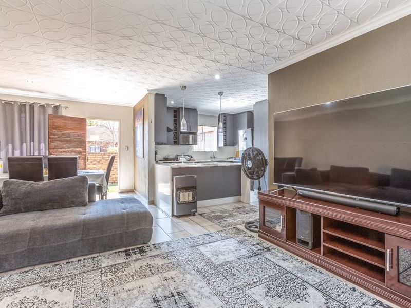 Open-plan living and kitchen area featuring tiled floors, a textured ceiling, and modern kitchen cabinetry with an island.