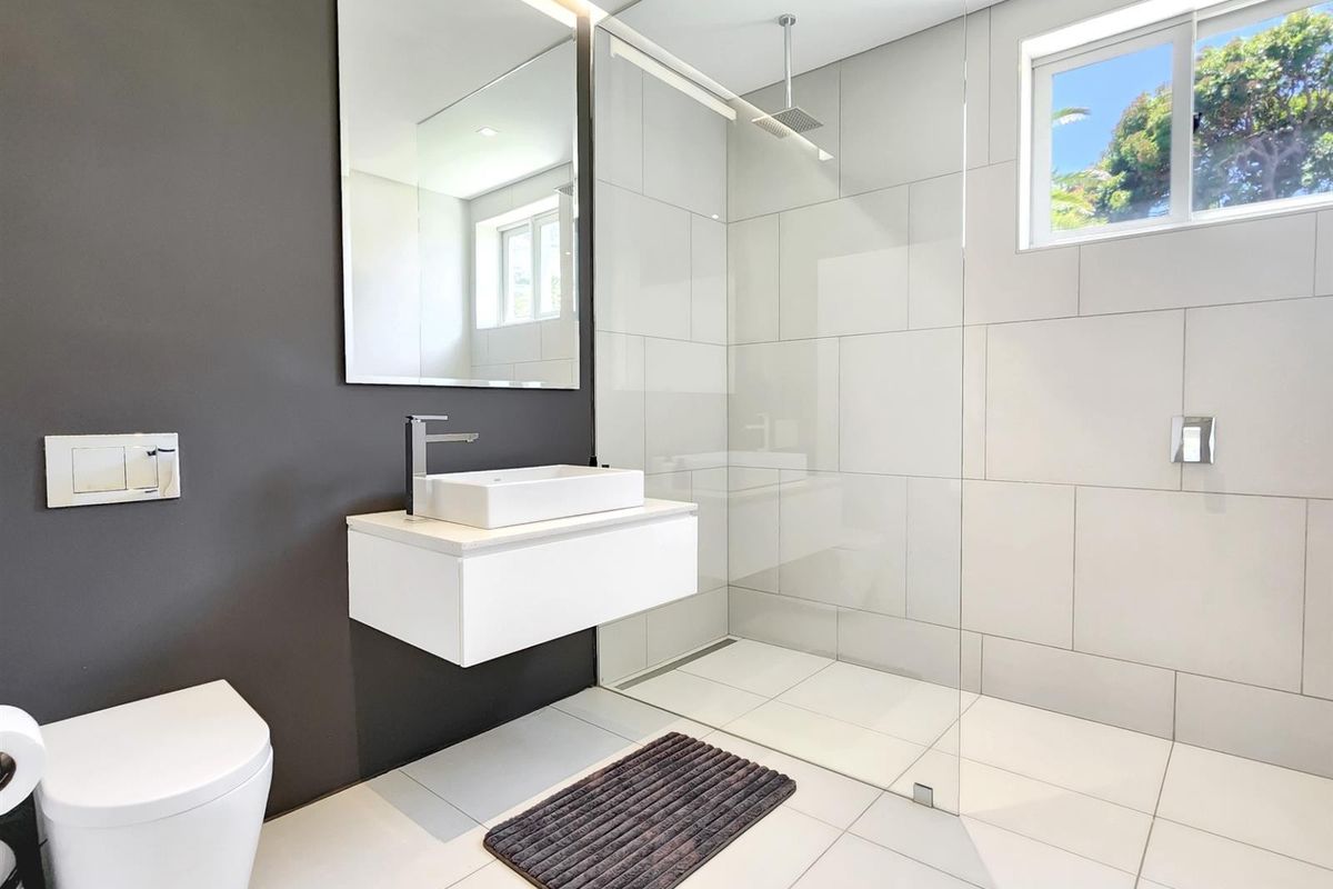 Modern bathroom featuring a wall-hung vanity, vessel sink, frameless glass walk-in shower with rain shower head, and wall-hung toilet with concealed cistern.