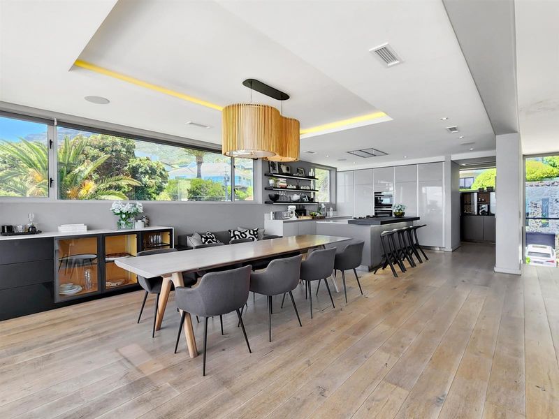 Modern open-plan living and dining area featuring high-end kitchen cabinetry, integrated appliances, hardwood flooring, and recessed ceiling lighting with a seamless flow.