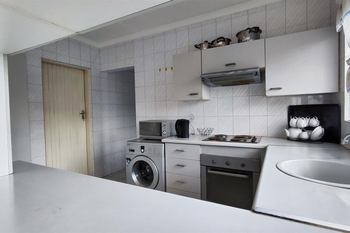 Functional kitchen featuring built-in cabinetry, electric hob, oven, extractor fan, and tiled splashbacks, offering a practical layout for daily meal preparation.