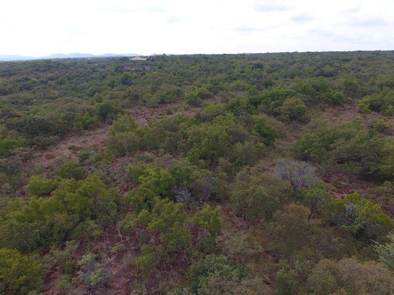 An aerial view of a large, undeveloped residential plot featuring natural bushveld vegetation and rocky terrain.
