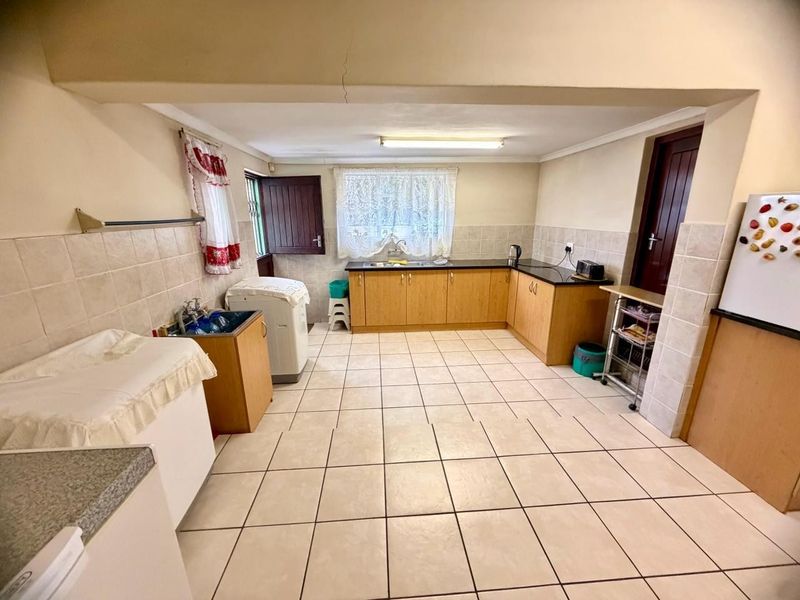 A functional kitchen featuring laminate cabinetry, granite countertops, tiled flooring, and a tiled backsplash, with a visible ceiling crack requiring attention.