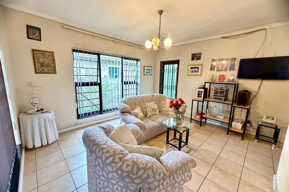 A functional living room featuring tiled flooring, security bars on windows, and a security gate, offering a neutral base for potential interior updates.