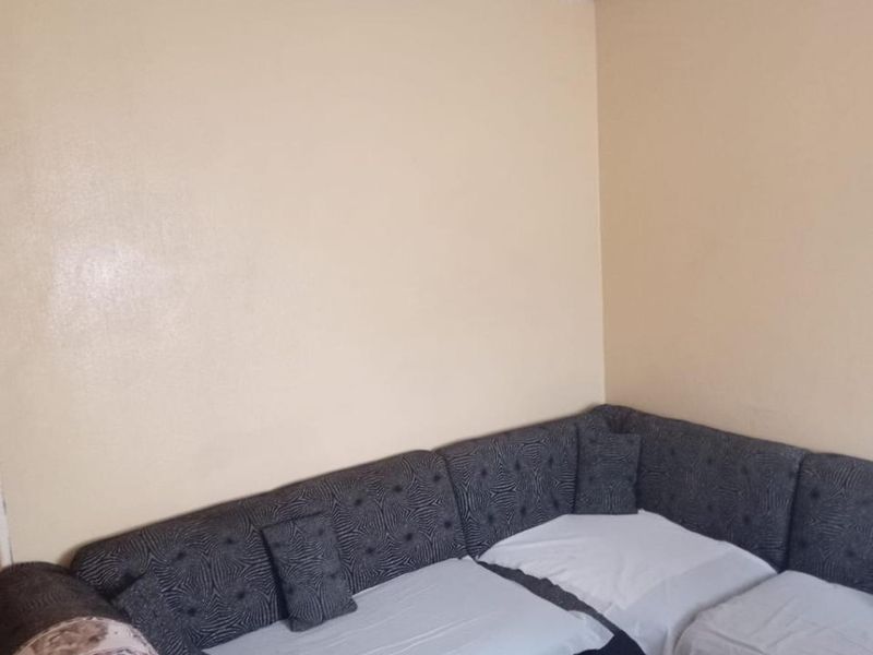 A living room area featuring tiled flooring and plain walls, currently requiring cosmetic updates to the ceiling and lighting fixtures.