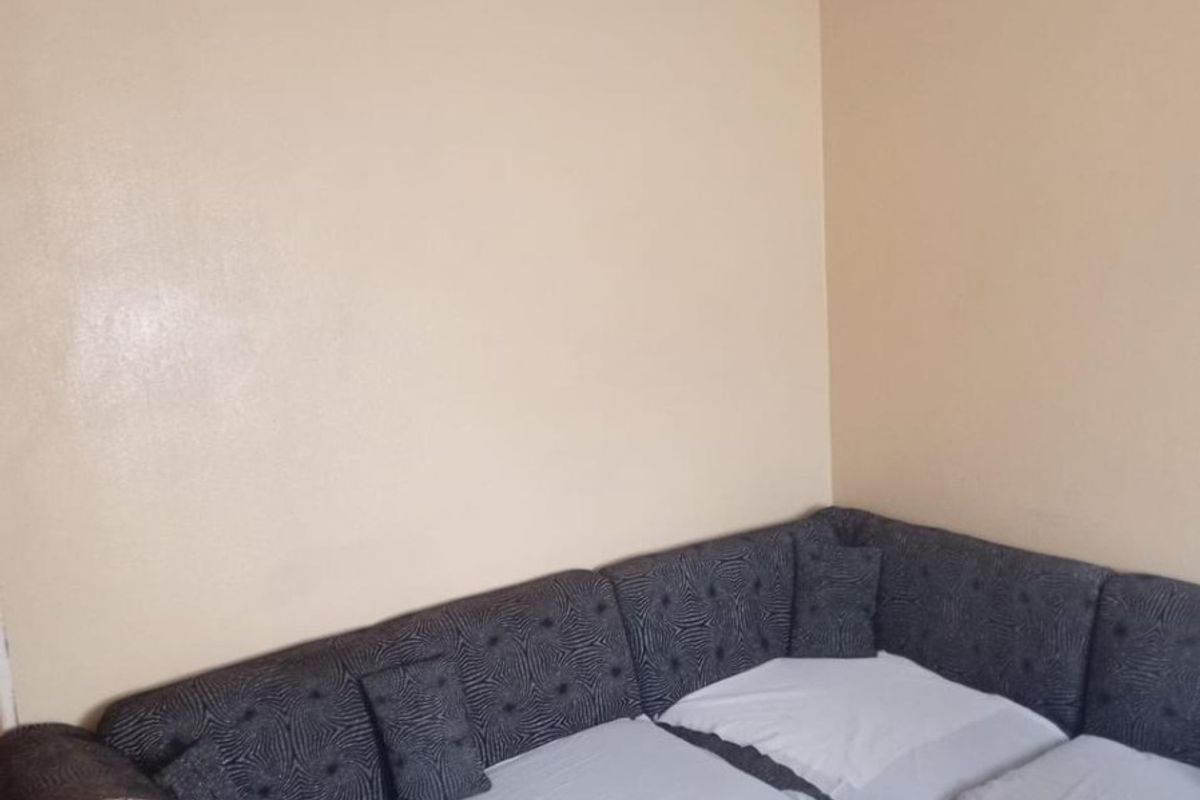 A living room area featuring tiled flooring and plain walls, currently requiring cosmetic updates to the ceiling and lighting fixtures.