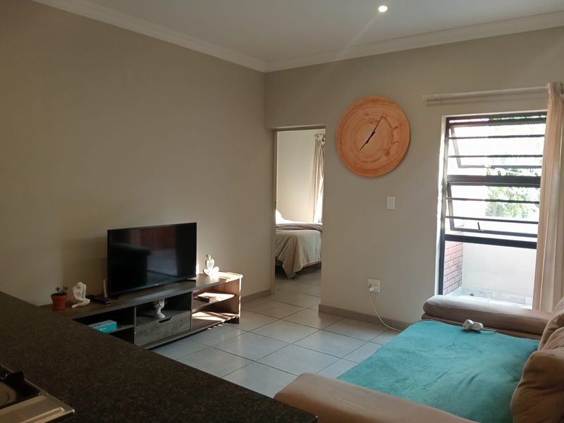 Open plan living area featuring tiled flooring, recessed lighting, and a large window, providing a functional space with direct access to the bedroom.
