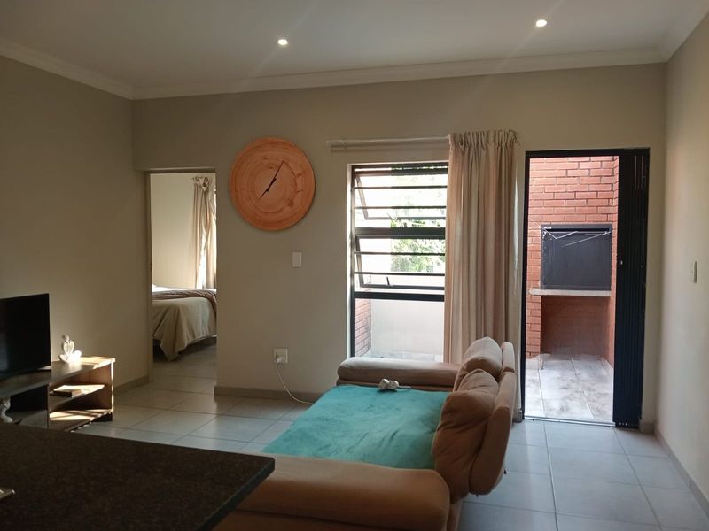 Living area featuring tiled floors, recessed lighting, and direct access to an outdoor patio with a built-in braai.
