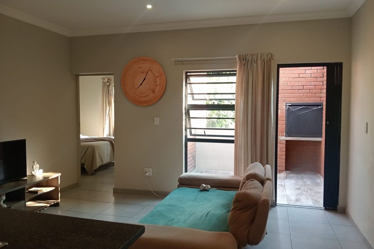 Living area featuring tiled floors, recessed lighting, and direct access to an outdoor patio with a built-in braai.