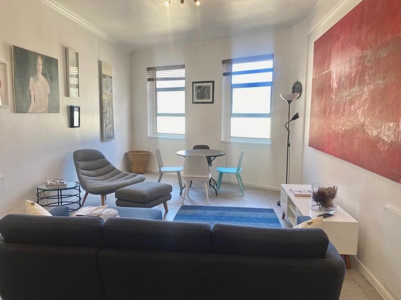 A bright living room featuring tiled flooring, coved ceilings, and dual windows that provide natural light to the space.