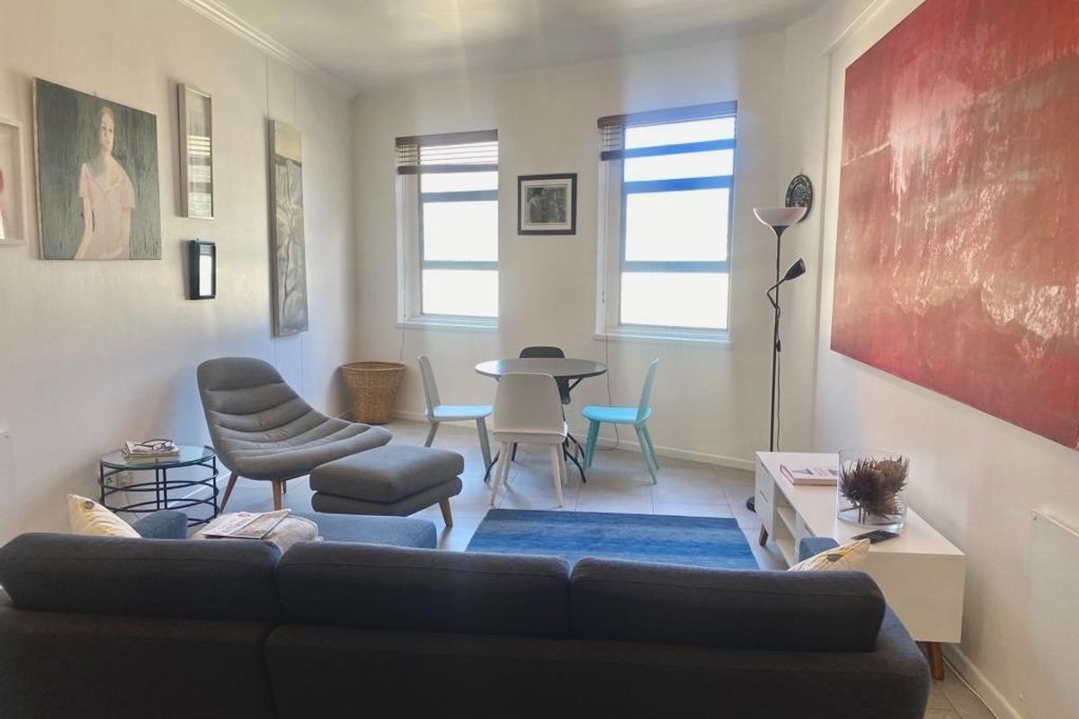 A bright living room featuring tiled flooring, coved ceilings, and dual windows that provide natural light to the space.