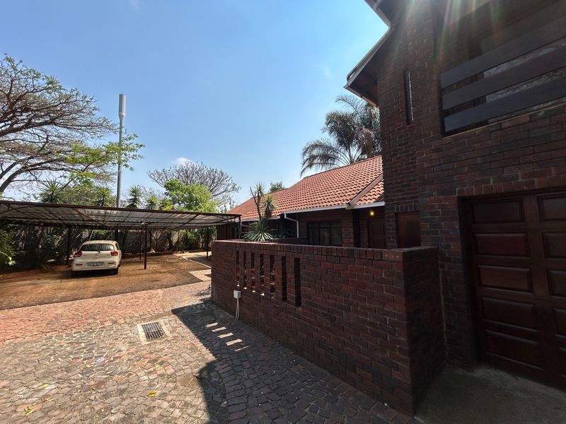 Front exterior view of a brick house featuring a tiled roof, a paved driveway, and a covered carport area.