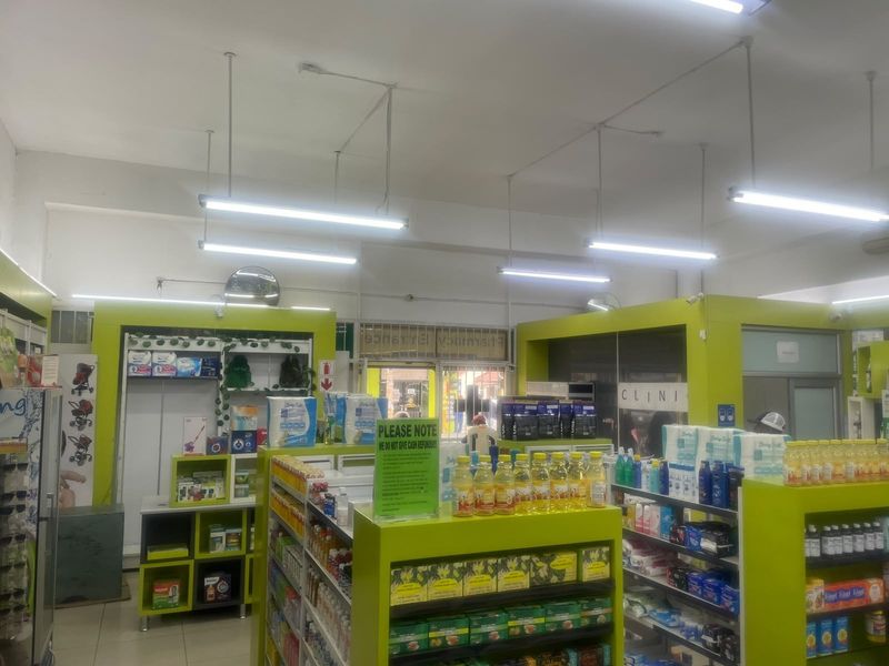 Interior view of a commercial pharmacy space featuring built-in shelving units, fluorescent lighting, and tiled flooring.