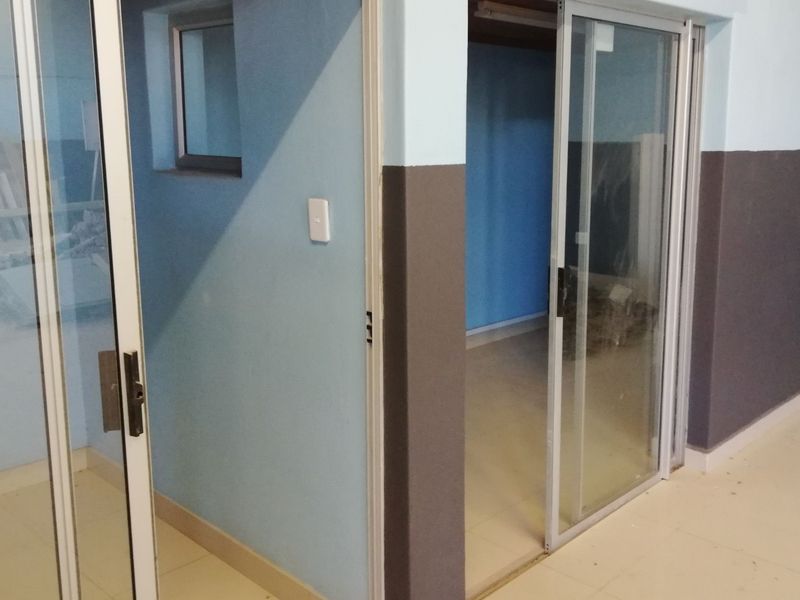 An empty commercial office space featuring tiled flooring and aluminium sliding glass doors, ready for custom fit-out.