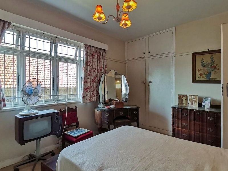 A bedroom featuring built-in cupboards and a multi-pane window, offering a dated aesthetic that could benefit from modern updates.