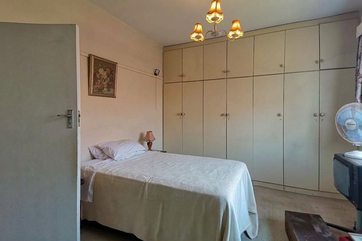 A bedroom featuring extensive built-in cupboards and a central light fixture, offering a functional space with potential for modern updates.