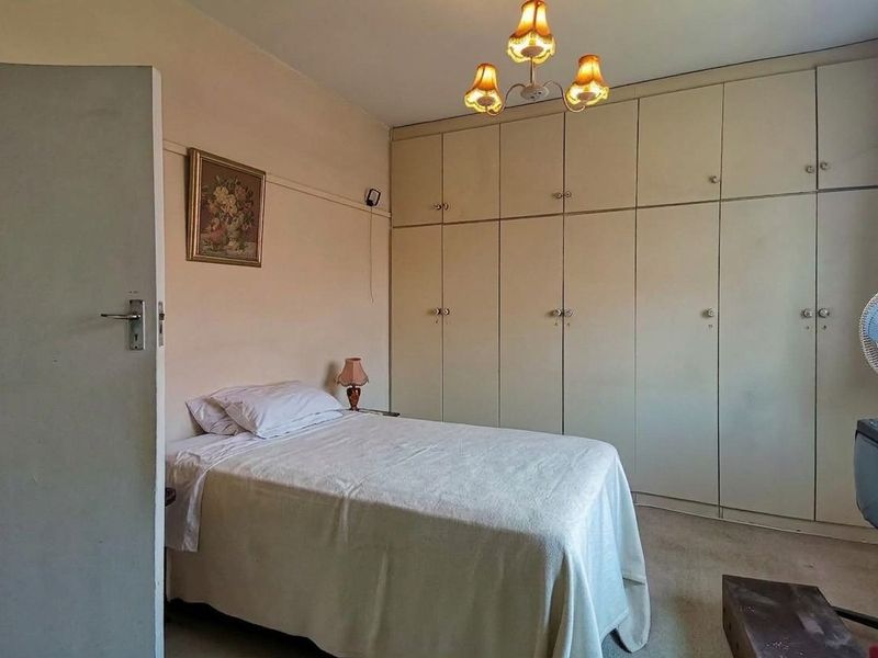 A bedroom featuring extensive built-in cupboards and a central light fixture, offering a functional space with potential for modern updates.