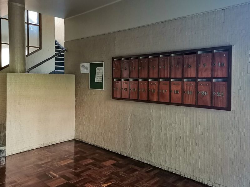Apartment building entrance lobby featuring parquet flooring, a wall-mounted bank of wooden mailboxes, and access to the communal staircase.