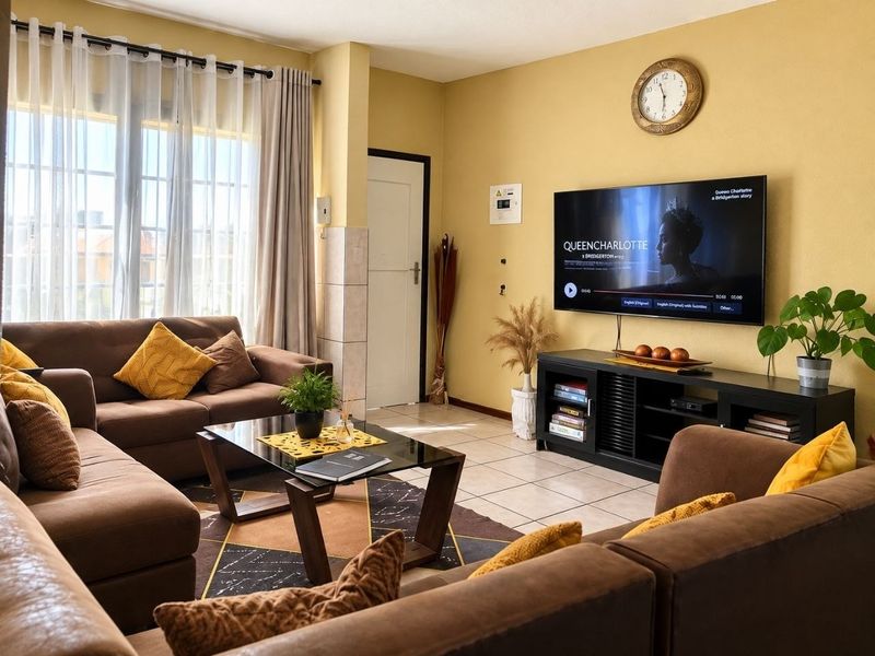A comfortable living room featuring tiled flooring, neutral wall tones, and a large window that allows for ample natural light.