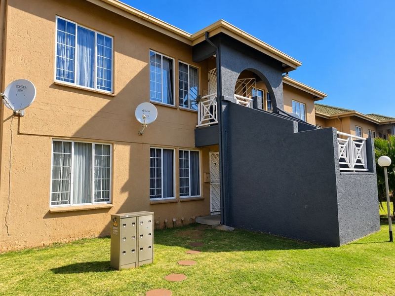 Front exterior view of a two-story apartment building featuring stucco walls, aluminum windows, and a private balcony with security gate access.