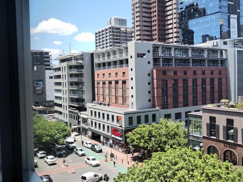An elevated urban view overlooking a busy city intersection with surrounding commercial buildings and street-level traffic.