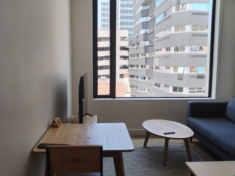 A bright living area featuring a large picture window with an urban city view.
