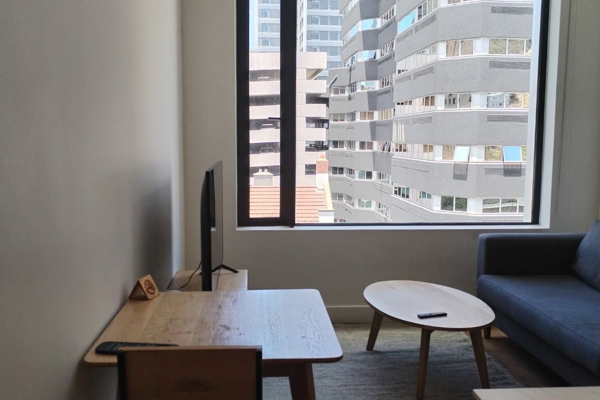 A bright living area featuring a large picture window with an urban city view.