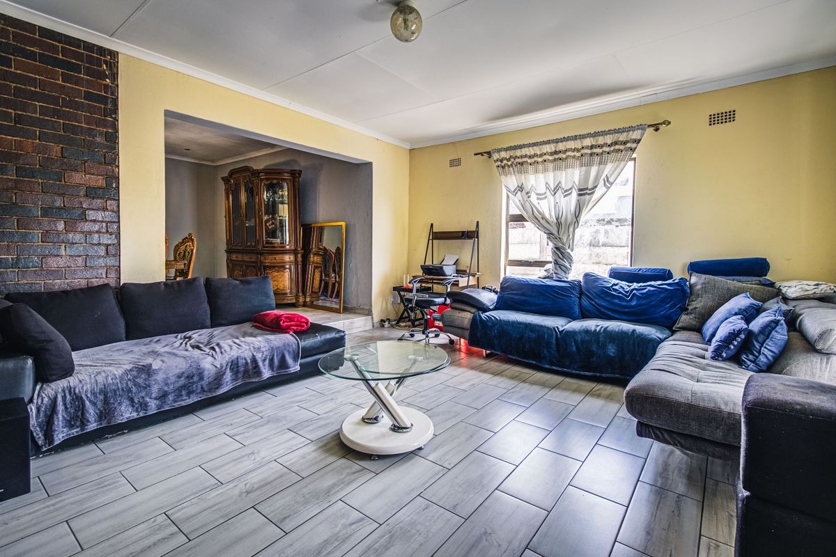 Spacious living room featuring a prominent exposed brick wall and modern tiled flooring, offering a versatile layout for comfortable family living.