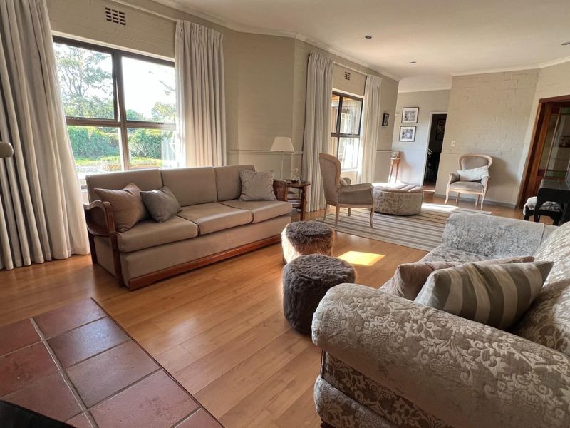 Spacious living room featuring laminate flooring, painted brick walls, and a tiled fireplace hearth, offering a bright and comfortable atmosphere.