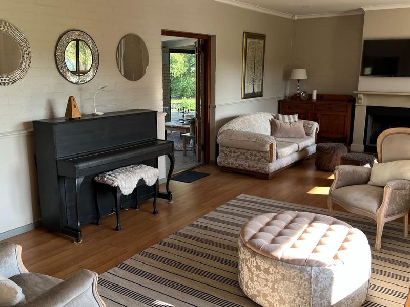 A spacious living room featuring laminate flooring, a classic fireplace with a mantelpiece, and a dado rail, with direct access to an outdoor patio area.