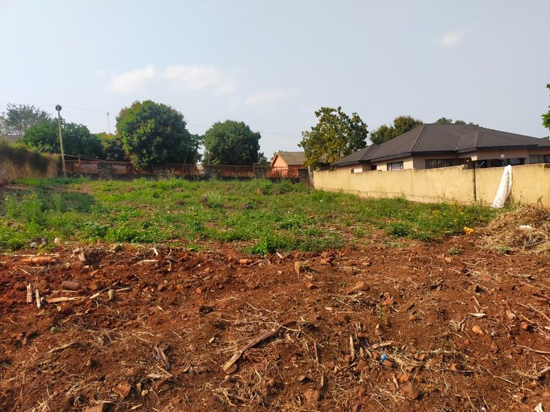 A vacant residential plot featuring cleared earth and perimeter boundary walls, offering a blank canvas for future development.