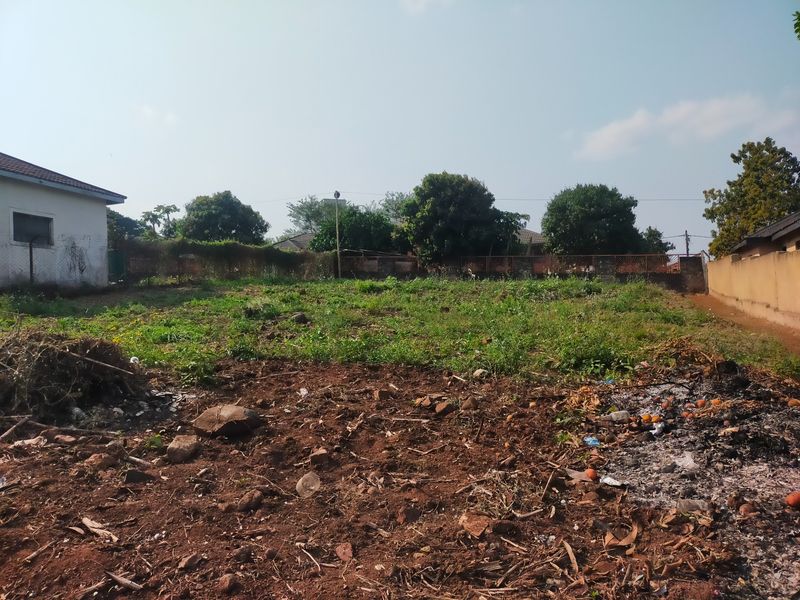 A vacant residential plot featuring a level terrain, boundary walls, and existing fencing, suitable for future development.