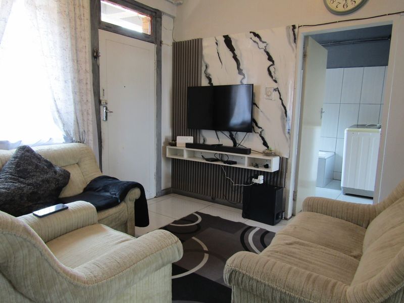 Living room featuring tiled flooring and a decorative wall-mounted media unit with marble-effect paneling.