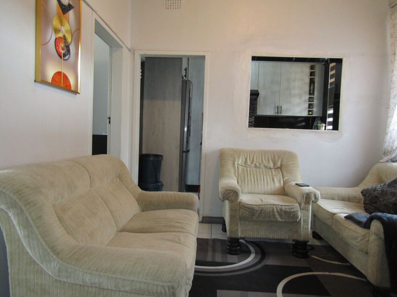 Living room featuring a serving hatch connecting to the kitchen area and tiled flooring throughout.