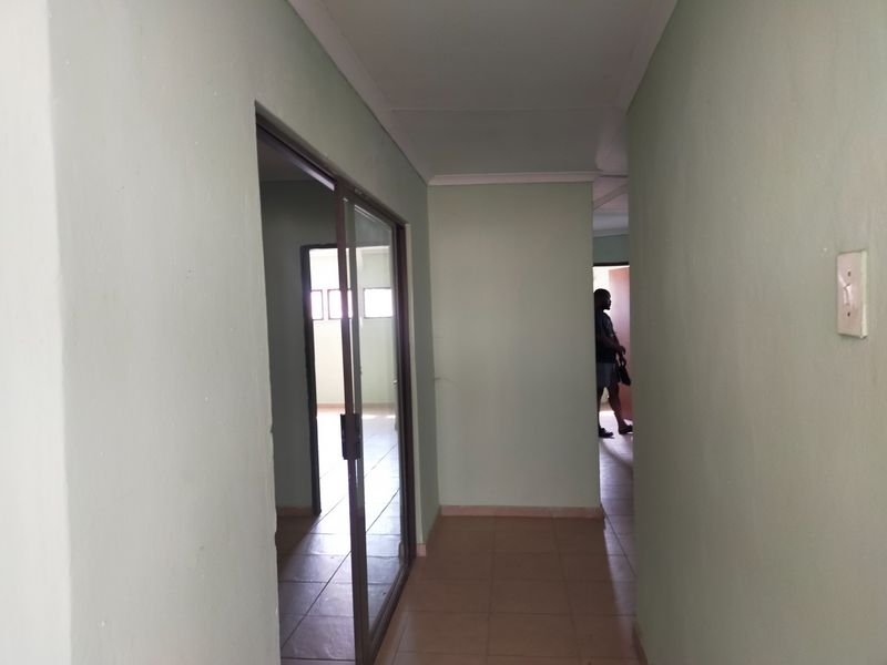 A functional hallway featuring tiled flooring and a sliding glass door providing access to an adjacent office space.