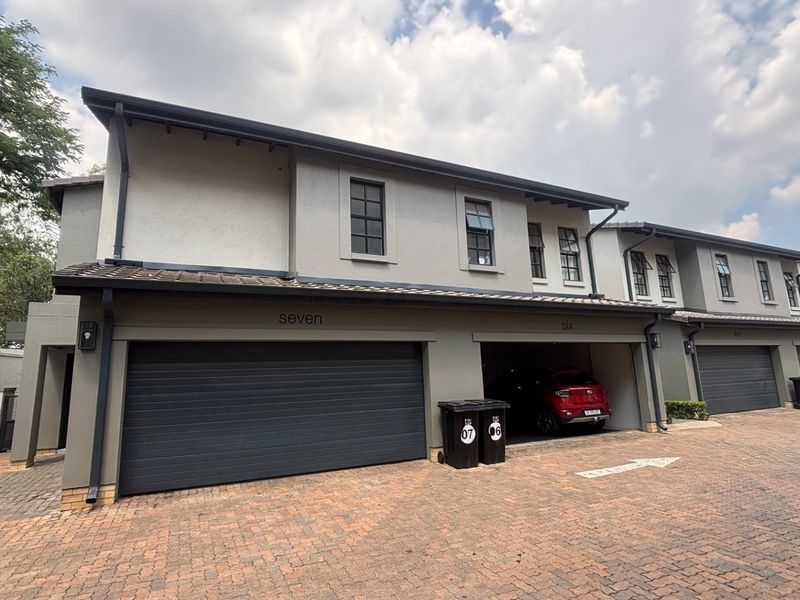 Front elevation of a modern townhouse complex featuring paved driveway access and multiple automated garage units.