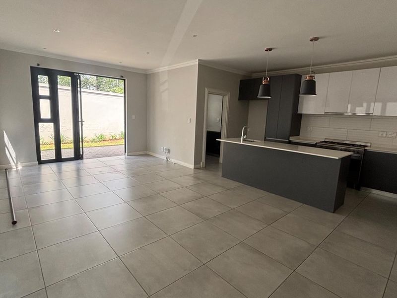 Modern open-plan living area featuring a sleek kitchen with island, gas stove, and large bi-fold doors leading to the rear patio.
