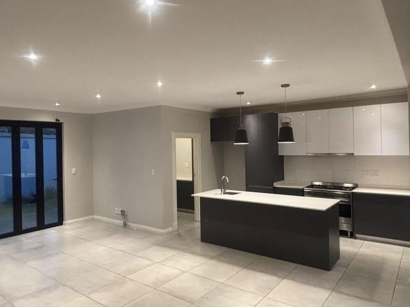 Spacious open-plan living and kitchen area featuring modern cabinetry, a central island, tiled floors, and bi-fold doors leading to the exterior.