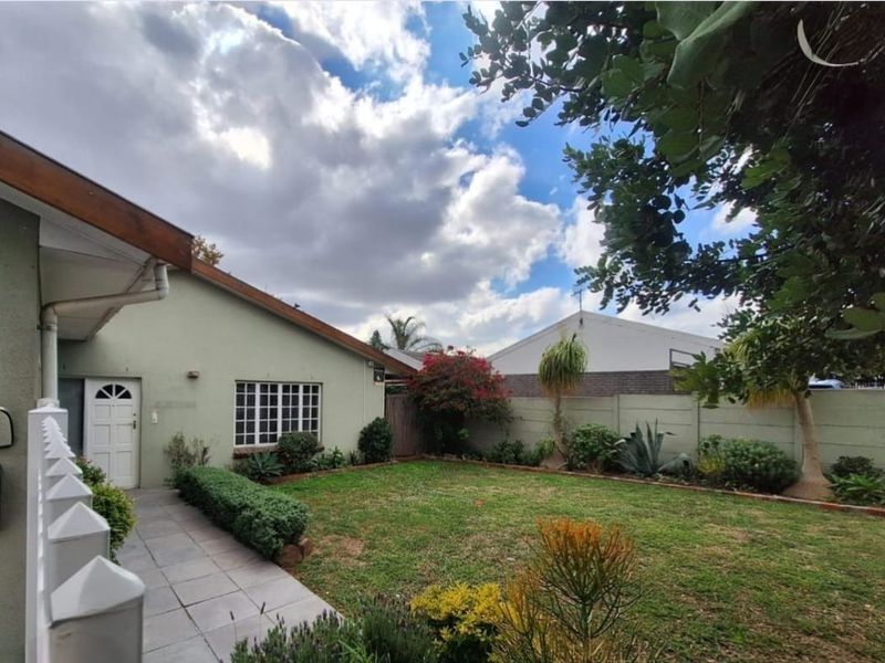 A well-maintained front garden featuring a paved walkway leading to the entrance, bordered by established landscaping and a secure precast boundary wall.