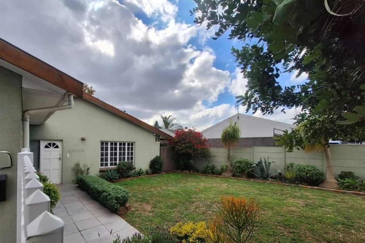 A well-maintained front garden featuring a paved walkway leading to the entrance, bordered by established landscaping and a secure precast boundary wall.